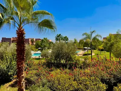 a palm tree in a garden with a pool at Luxurious Stay at Prestigia Golf Marrakech with Golf Course, Pool, and Breathtaking Atlas Mountains View in Marrakech