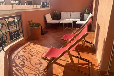 a balcony with a red chair and a couch at Sunny terrace & comfy beds in Marrakech in Marrakech