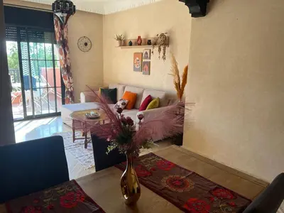 a living room with a vase of flowers on a table at Marrakech Atlas Golf Resort appartement 2 chambres,Piscines in Marrakech