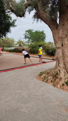 two children are playing with a long rope under a tree at Marrakech Atlas Golf Resort appartement 2 chambres,Piscines in Marrakech