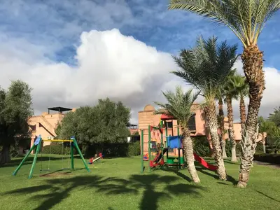 a playground in a yard with palm trees at Marrakech Atlas Golf Resort appartement 2 chambres,Piscines in Marrakech