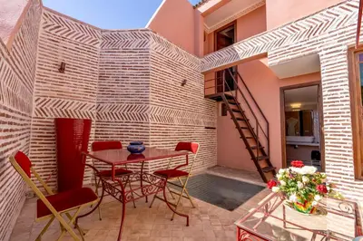 a patio with a table and chairs and a staircase at Riad Dombaraka in Marrakech