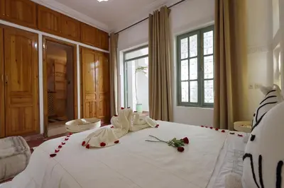 a bedroom with a large white bed with roses on it at RIAD CHOUKRI in Marrakech