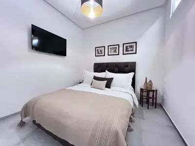 a white bedroom with a large bed and a flat screen tv at S_house in Marrakech