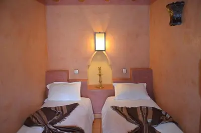 two beds in a room with a cross on the wall at GREEN HOUSE in Marrakech