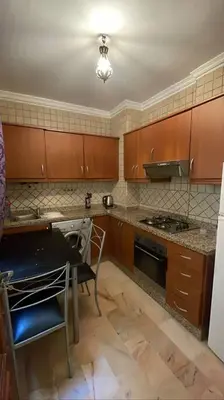a kitchen with wooden cabinets and a table and a stove at Appartement Bellevue in Marrakech
