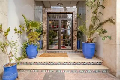 a lobby with blue pots of plants in front of a door at stylish appartment heart of gueliz in Marrakech