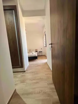 a hallway with a wooden door and a room with a couch at NOUR appartement in Marrakech