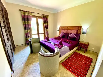 a bedroom with a purple bed and a chair at Villa Agdal in Marrakech
