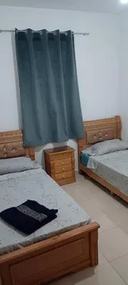 a bedroom with two beds and a blue curtain at appartement Les Palmeraies in Marrakech