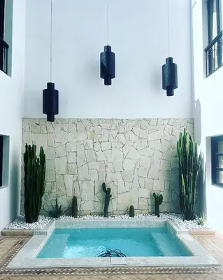 a swimming pool in the middle of a room with plants at Riad Belharra in Marrakech
