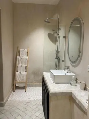 a bathroom with a sink and a mirror and a chair at Riad Belharra in Marrakech