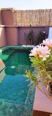 a swimming pool in a house with flowers at Riad Belharra in Marrakech
