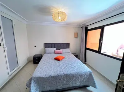 a bedroom with a bed with an orange pillow on it at The Majestic Marrakesh Duplex in Marrakech