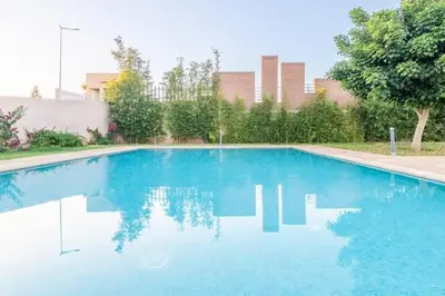 a swimming pool with blue water in a yard at Magnifique appartement Les perles de marrakech lux avec 2 piscines in Marrakech