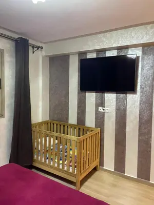 a room with a crib and a flat screen tv at Magnifique appartement Les perles de marrakech lux avec 2 piscines in Marrakech