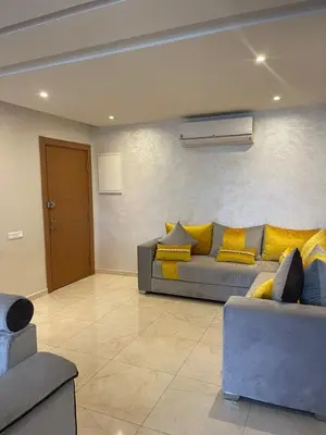 a living room with a couch and yellow pillows at Magnifique appartement Les perles de marrakech lux avec 2 piscines in Marrakech