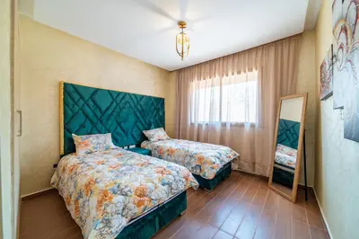 a bedroom with two beds and a mirror at Résidence Coralia les orangers in Marrakech