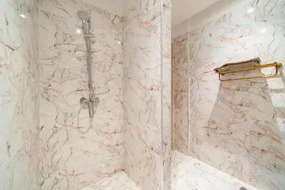 a bathroom with a shower with a marble wall at Résidence Coralia les orangers in Marrakech