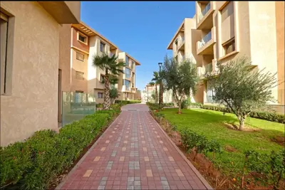 a brick walkway between two apartment buildings at Résidence Coralia les orangers in Marrakech