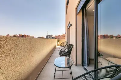 a balcony with two chairs and a table on a building at Duplex de Luxe Victor Hugo Gueliz in Marrakech