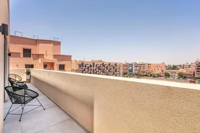 a balcony with two chairs and a view of a city at Duplex de Luxe Victor Hugo Gueliz in Marrakech
