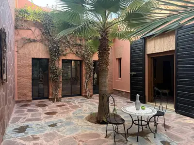 a courtyard with a palm tree and a table and chairs at Superbe villa avec piscine privée - Golf Amelkis in Marrakech