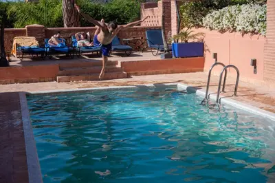a man jumping into a swimming pool at Superbe villa avec piscine privée - Golf Amelkis in Marrakech