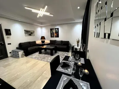 a living room with a black couch and a table at Appartement Bagatelle in Marrakech