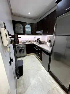 a small kitchen with a refrigerator and a dishwasher at Appartement Bagatelle in Marrakech
