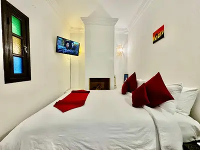 a bedroom with a large white bed with red pillows at Riad Iklil in Marrakech