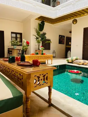 a living room with a pool with a table and a couch at Riad Deha & Spa in Marrakech