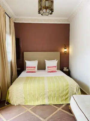 a bedroom with a bed with two pink pillows at Riad Deha & Spa in Marrakech