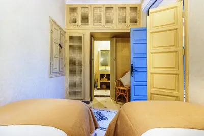 two beds in a bedroom with blue and yellow doors at Riad Berrima - Breakfast - 10mn from Jamaa Al Fna in Marrakech