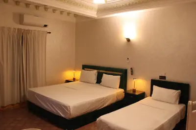 two beds in a hotel room with two lamps at Villa Gardens Diafa in Marrakech