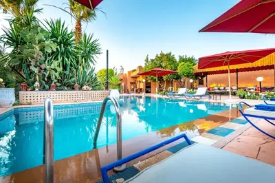 a swimming pool with chairs and umbrellas in a resort at Villa Gardens Diafa in Marrakech
