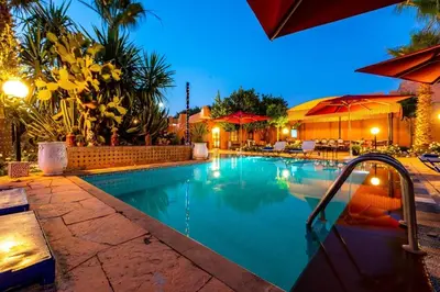 a swimming pool in a resort at night at Villa Gardens Diafa in Marrakech