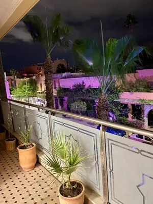a balcony with palm trees and purple lights at Golden house in Marrakech