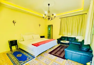 a bedroom with a bed and a couch and a chandelier at Villa Baddi Marrakech in Marrakech