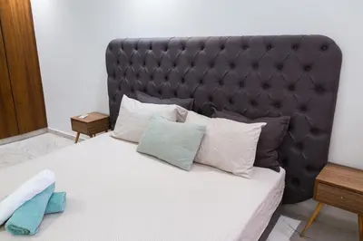 a bed with a black padded headboard and pillows at A Place To Call Home - Downtown in Marrakech