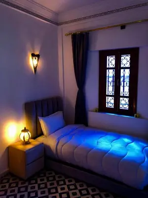 a bedroom with a blue bed and a window at Riad Amely in Marrakech