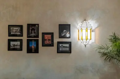 a light on a wall with pictures on it at Riad Privé Dar L'Étoile - Jacuzzi Piscine & Petit Déj inclus in Marrakech