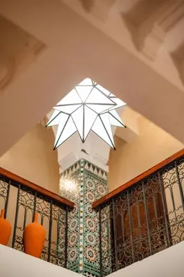 a stairwell with a balcony with orange vases at Riad Privé Dar L'Étoile - Jacuzzi Piscine & Petit Déj inclus in Marrakech