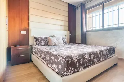 a bedroom with a bed with a black and white comforter at Magnifique Appartement lux - Perles de Coralia in Marrakech