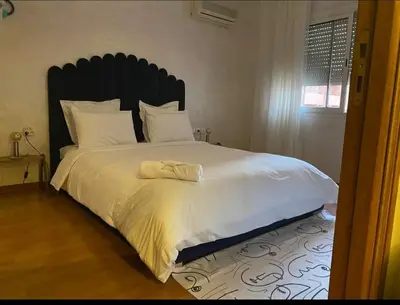 a bedroom with a large white bed with a black headboard at Appartement cosy quartier au centre de Marrakech Gueliz in Marrakech