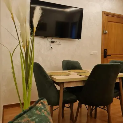 a dining room table with chairs and a television on the wall at Appartement cosy quartier au centre de Marrakech Gueliz in Marrakech