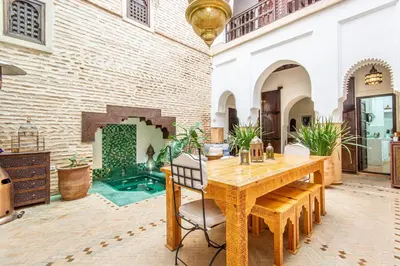 a dining room with a wooden table and a brick wall at Riad El Faris Exclusif-Included Moroccan Breakfast in Marrakech