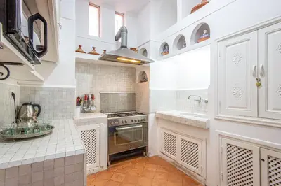 a kitchen with white cabinets and a sink and a stove at Riad El Faris Exclusif-Included Moroccan Breakfast in Marrakech