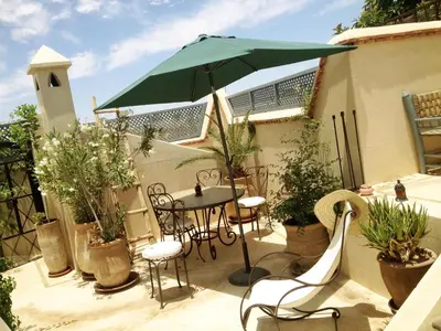 a patio with a table and a green umbrella at Riad of The Light in Marrakech