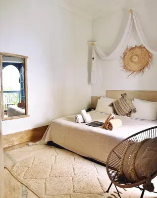 a bedroom with a bed with a mirror and a chair at Riad of The Light in Marrakech